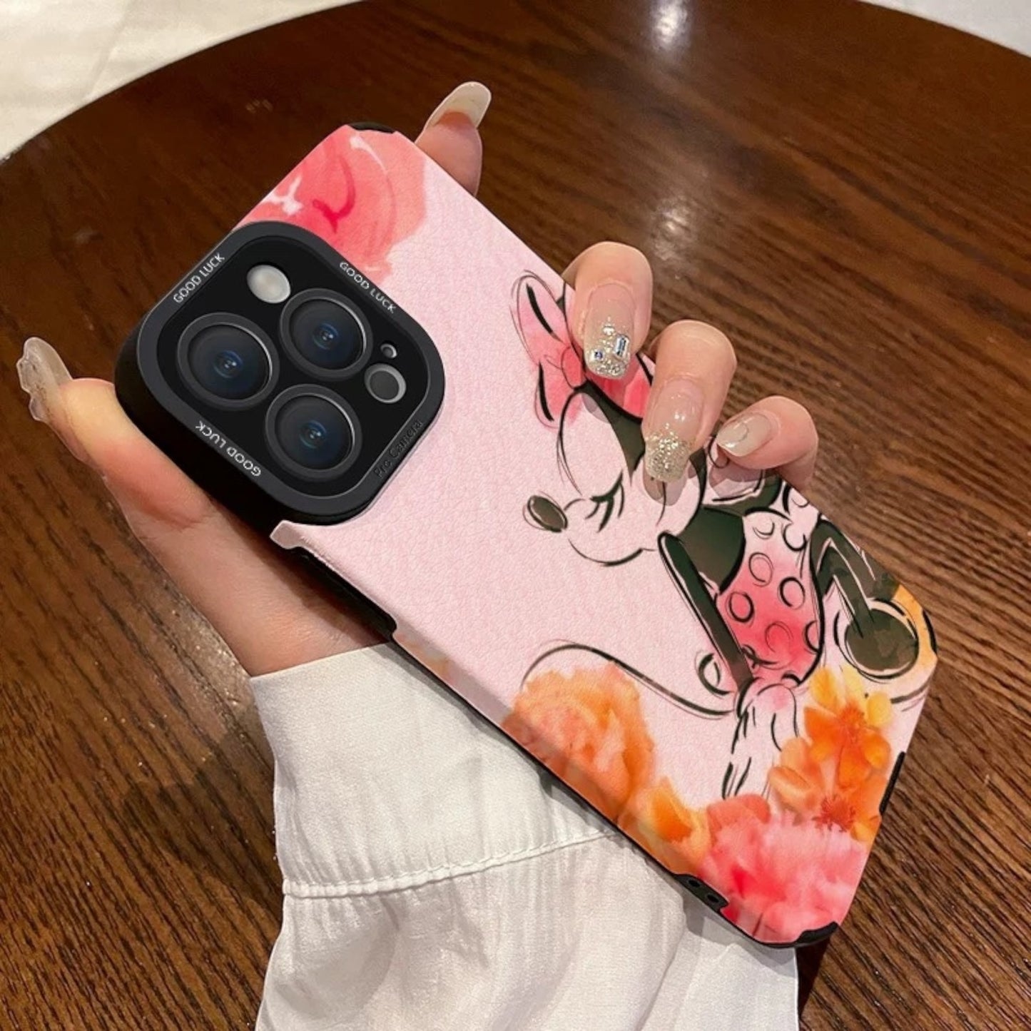 Pink iPhone case with cartoon character Disney Minnie Mouse design held by a hand