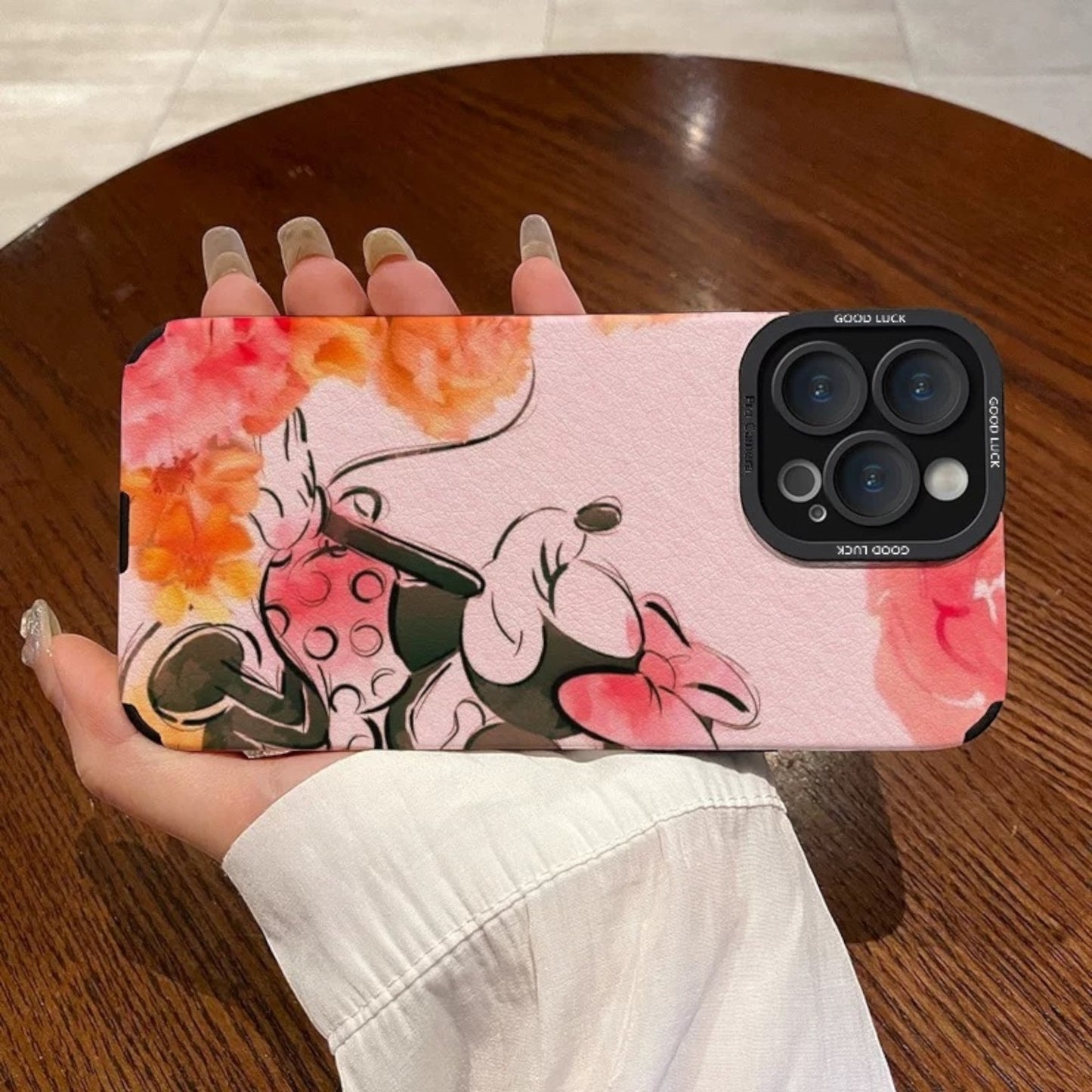Pink iPhone case with cartoon character Disney Minnie Mouse design held by a hand