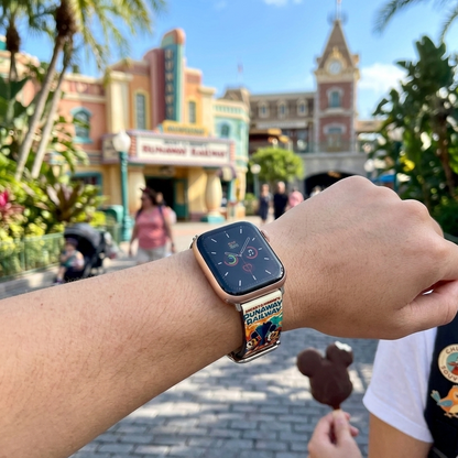Person wearing a smartwatch with a colorful band in an amusement park setting