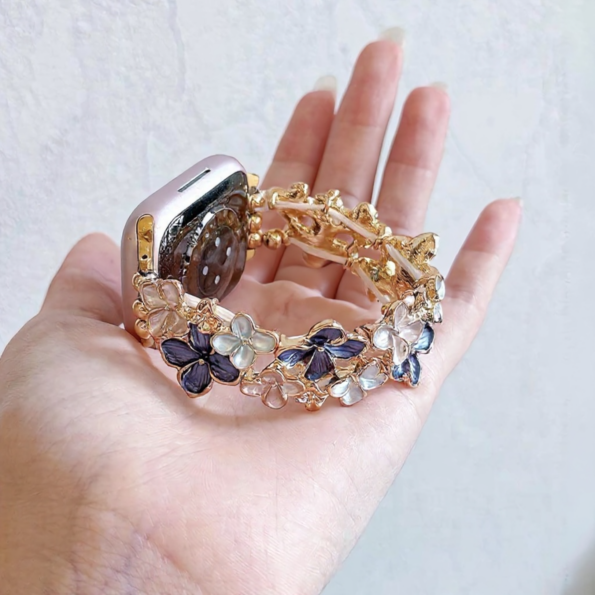 gold-apple-watch-bracelet-purple-enamel-flowers-rhinestones-holding-in-hand