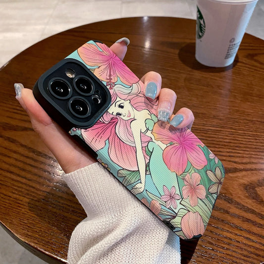 iPhone case with Ariel in floral design held by a hand on a wooden table with a Starbucks cup in the background.