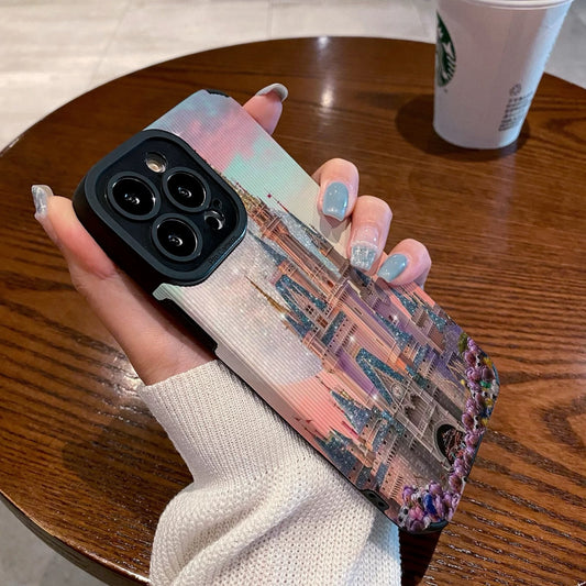 Person holding a iphone with a colorful iphone case featuring a disney theme park castle design, Starbucks cup in the background.