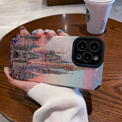 Person holding a iphone with a colorful iphone case featuring a disney theme park castle design, Starbucks cup in the background.