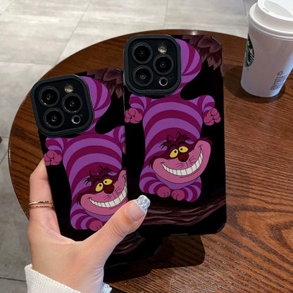 Hand holding a iPhone case with a Cheshire Cat of Alice in Wonderland on a wooden table with a Starbucks cup.