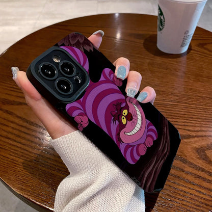 Hand holding a iPhone case with a Cheshire Cat of Alice in Wonderland on a wooden table with a Starbucks cup.