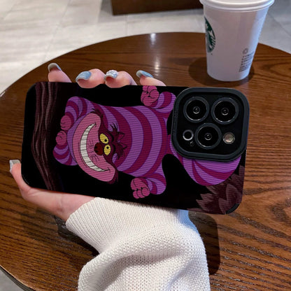 Hand holding a iPhone case with a Cheshire Cat of Alice in Wonderland on a wooden table with a Starbucks cup.