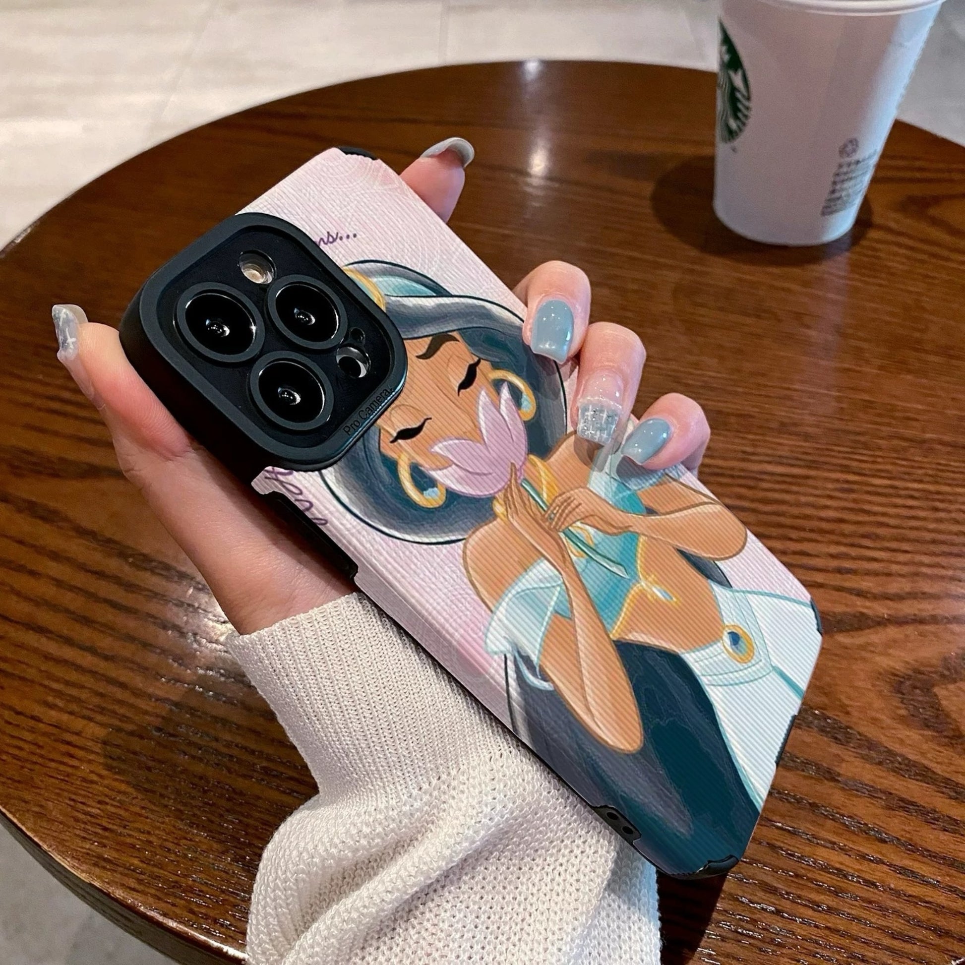 iPhone case with an illustration of a Jasmine holding a flower, held by a hand on a wooden table with a Starbucks cup.