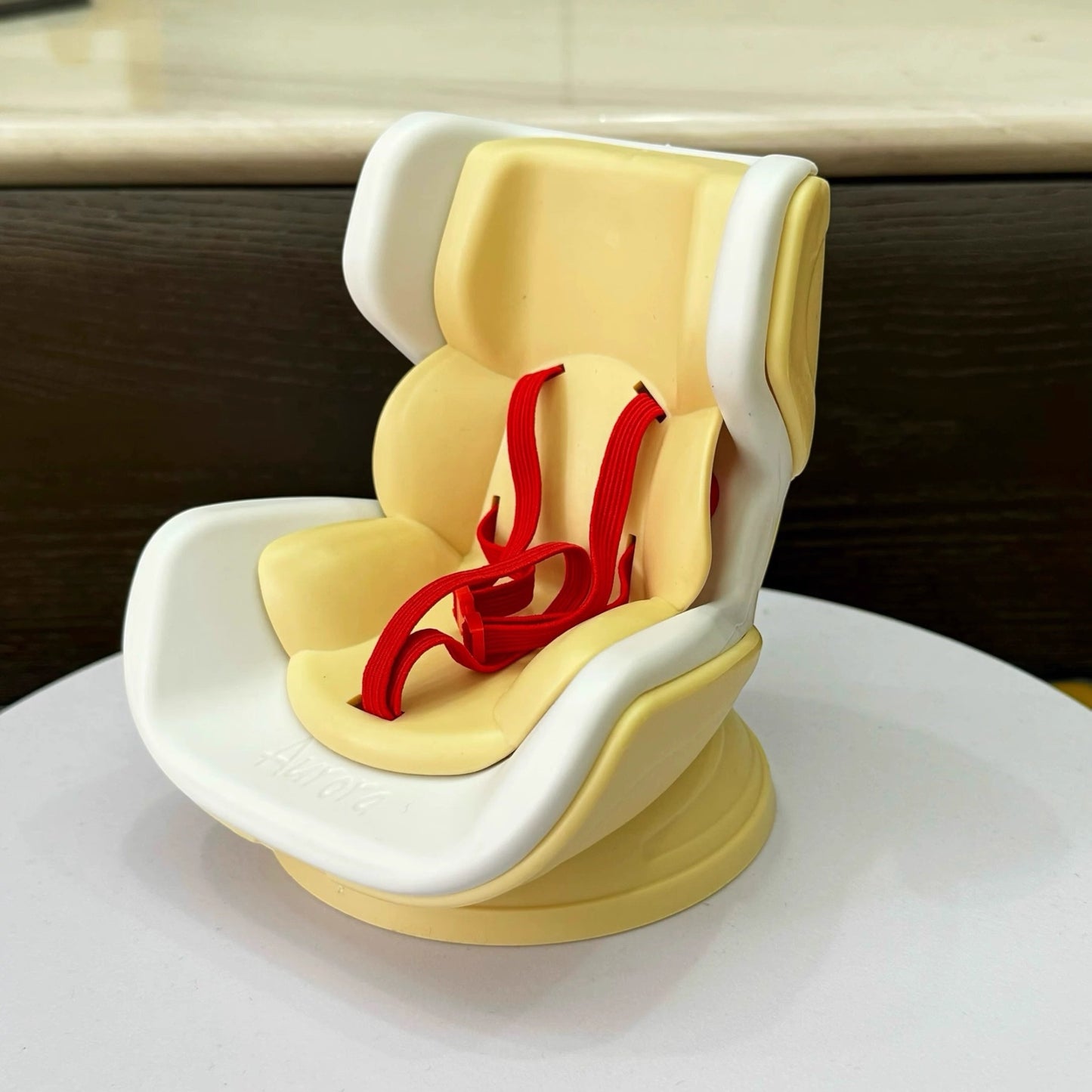 Yellow and white baby seat with red straps on a white surface