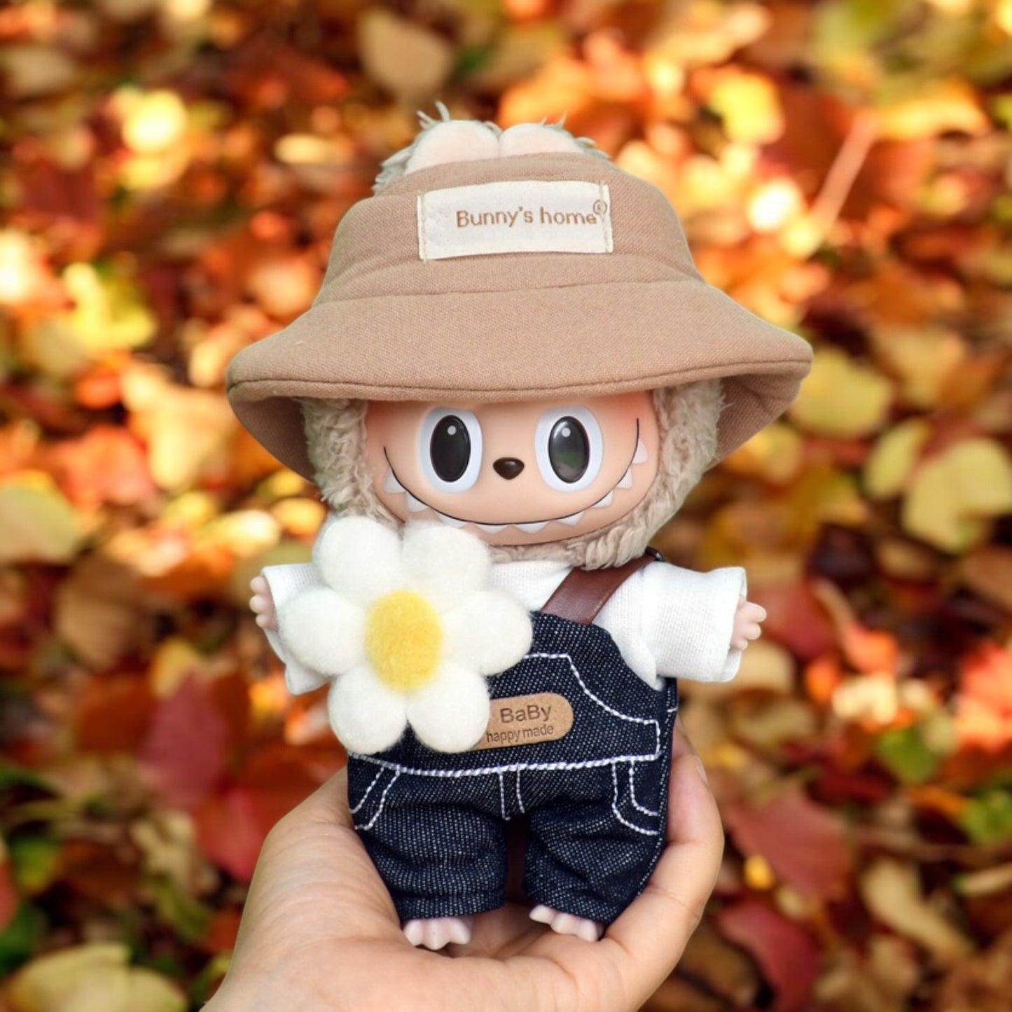 A Labubu Doll wearing a fall in Winter outfits holding by a hand in the forrest