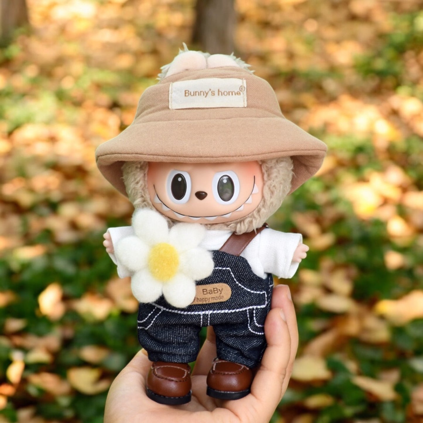 A Labubu Doll wearing a fall in Winter outfits holding by a hand in the forrest