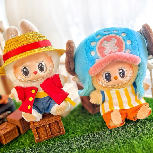 Two plush toys resembling characters One Piece Luffy and Chopper from a popular anime series on grass with a blurred background.