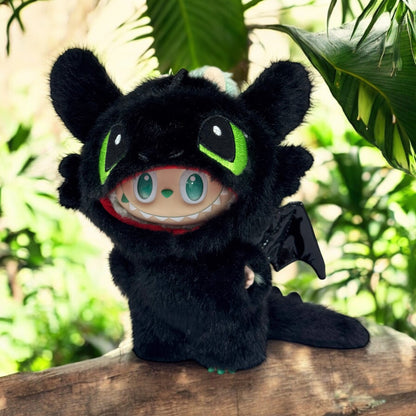 Labubu Plush toy wearing a toothless Costume - a dragon with black fur, green eyes, and red mouth in a forest setting.