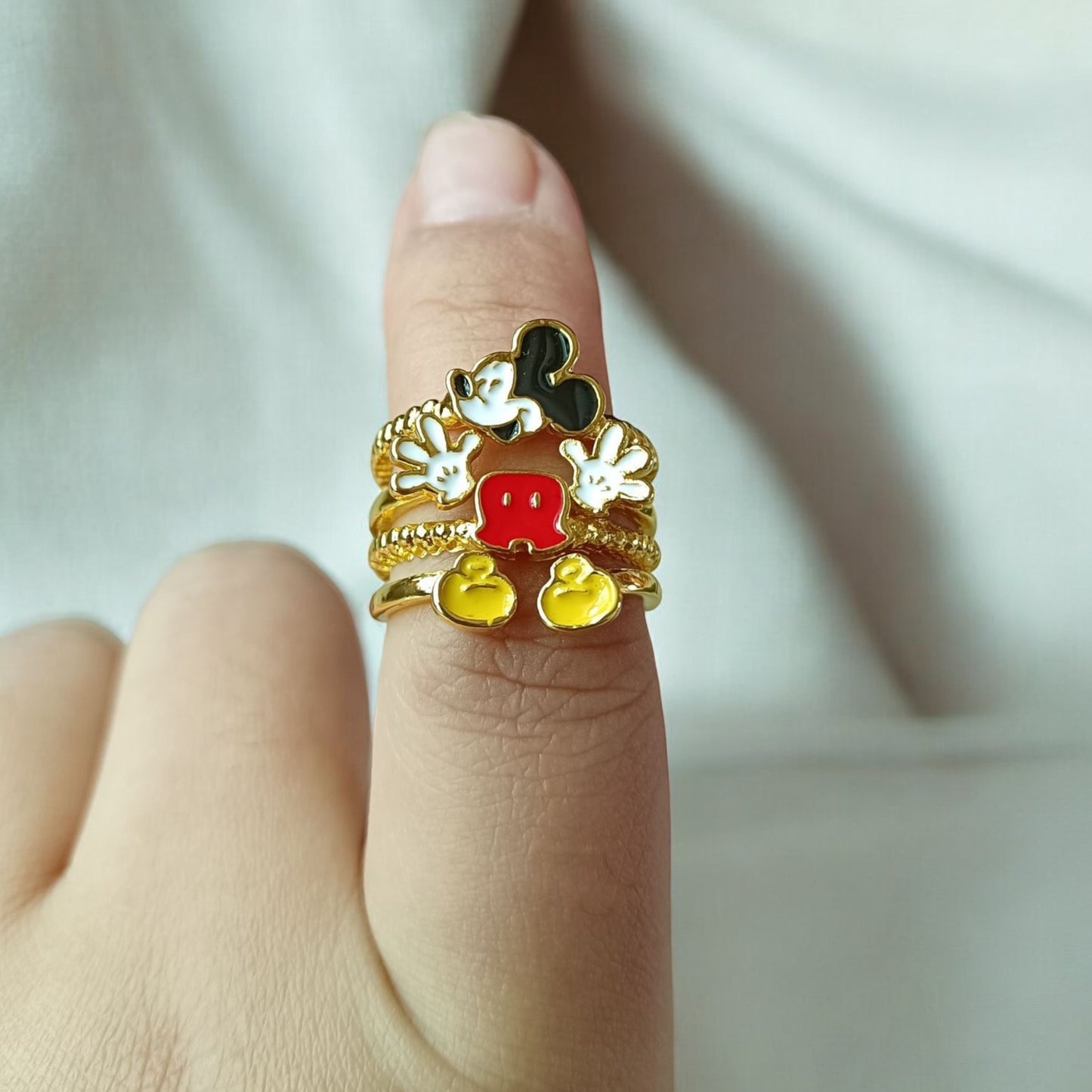 Hand wearing a Gold cartoon-themed Vintage Mickey Mouse ring with a white background