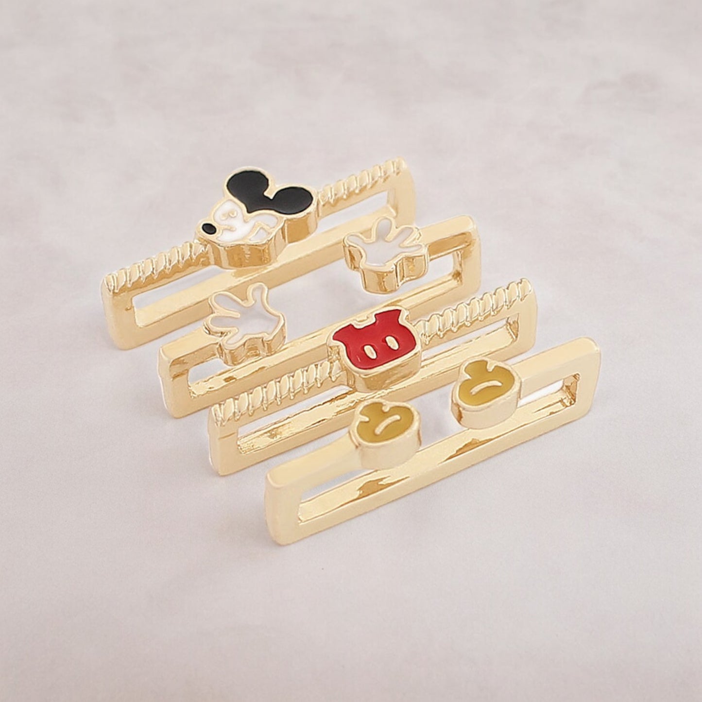 Set of gold hair clips with cartoon character vintage mickey mouse designs on a light gray background