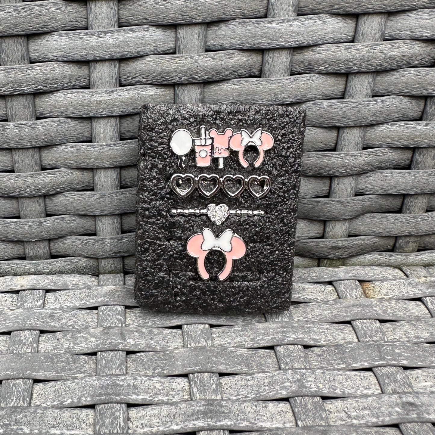 Black glittery case with decorative minnie mouse theme park snack charms on a woven surface