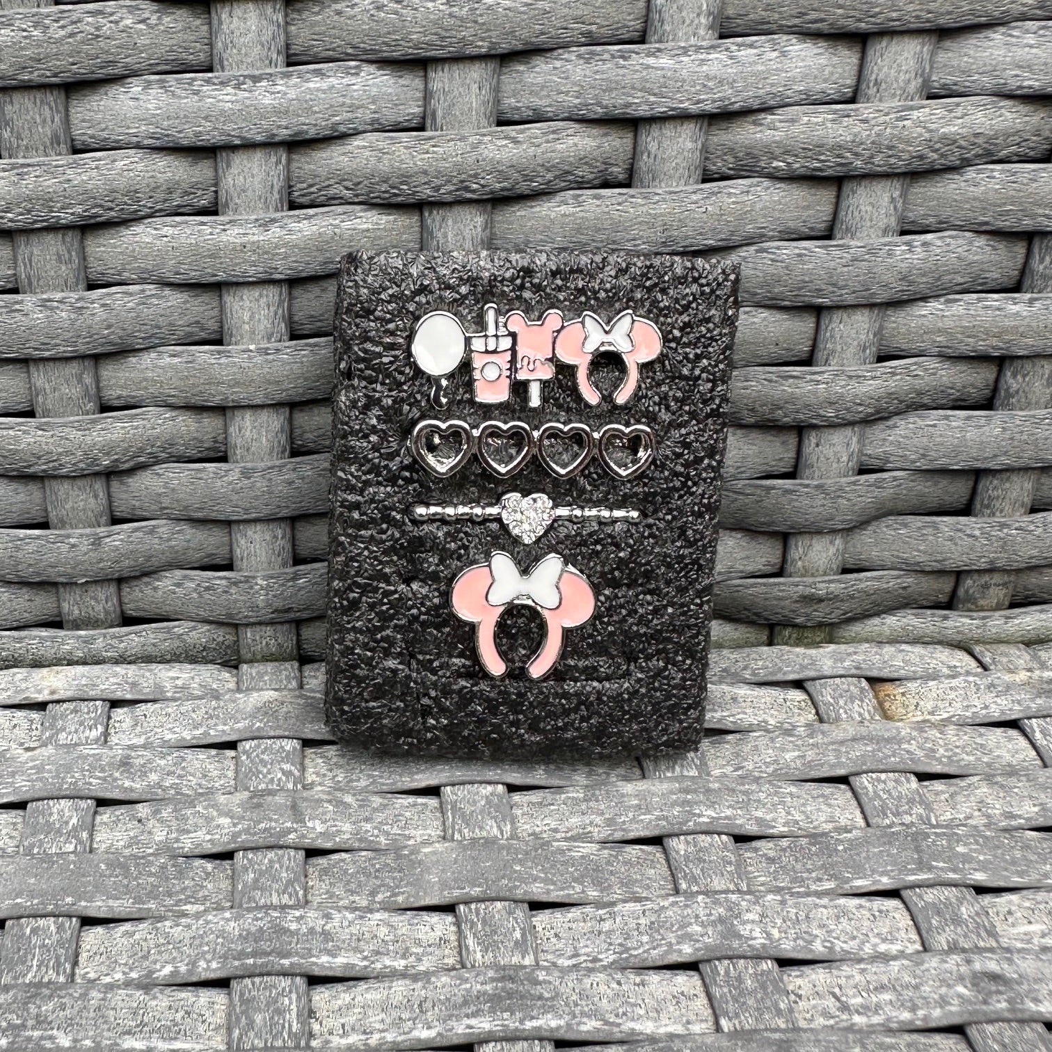 Black glittery case with decorative minnie mouse theme park snack charms on a woven surface