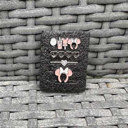 Black glittery case with decorative minnie mouse theme park snack charms on a woven surface
