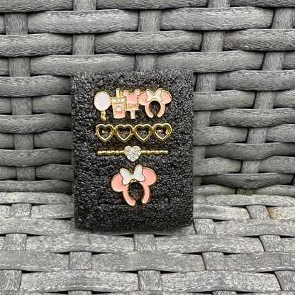 Set of decorative minnie mouse theme park snack charms on a textured black background